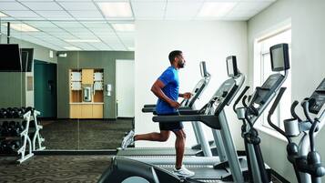 A gym with treadmills, a mirrored wall, and a weight rack.