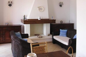 Un soggiorno con camino, due divani, un tavolo da pranzo e un mobile in legno.