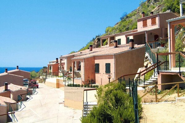 Una zona residenziale costiera con case a schiera, cielo sereno e vista sul mare.