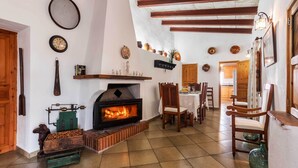 A cozy living room with a fireplace, wooden beams, and rustic decor. - Finca Sa Bastida (Sant Joan)