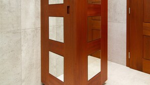Een houten garderobe met gespiegelde deuren en verschillende vakken.