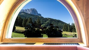 Una ventana con vista a una montaña y follaje.