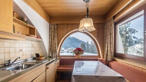 Una cocina compacta con asiento junto a la ventana, una mesa y vistas a un paisaje nevado.