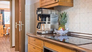 A kitchen with a coffee maker, a stainless steel refrigerator, wooden cabinets, and a pineapple on the counter.