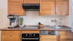 A kitchen with wooden cabinets, a built-in oven, a coffee maker, and a fruit bowl.