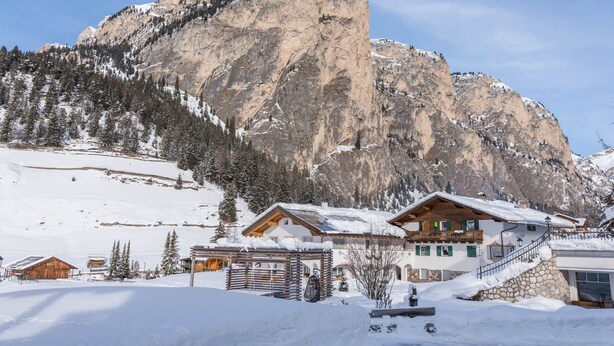 A mountain lodge with a wooden exterior, a balcony, and a staircase leading to the entrance.