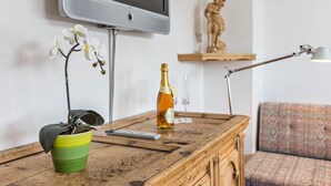 A wooden table with a remote control, a bottle of champagne, and a potted orchid.
