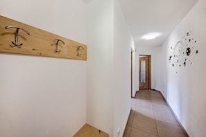 Un corridoio con una mensola in legno con ganci metallici, una porta in fondo e una parete decorata con un'immagine a tema spaziale.