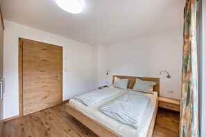 Una camera da letto con una porta in legno, un letto con lenzuola a righe, comodini e una lampada a soffitto.