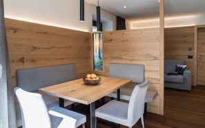 Un comedor moderno con una mesa de madera, sillas tapizadas de gris y un cuenco de fruta.