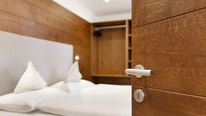 Une chambre à coucher en bois, avec un lit, des oreillers et une porte dotée d’une serrure.