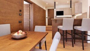 Une cuisine moderne avec des meubles en bois, un îlot central doté de tabourets de bar et un coin repas avec une table et des chaises en bois.