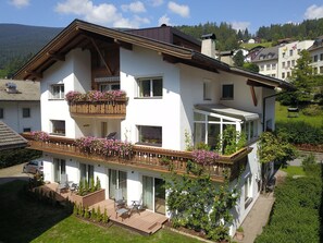 A two-story house with a balcony, a covered patio, and a view of the surrounding landscape.