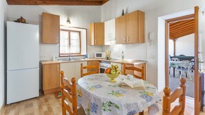 Une cuisine avec des meubles de rangement en bois, un réfrigérateur, un four à micro-ondes et une table à manger avec des chaises.