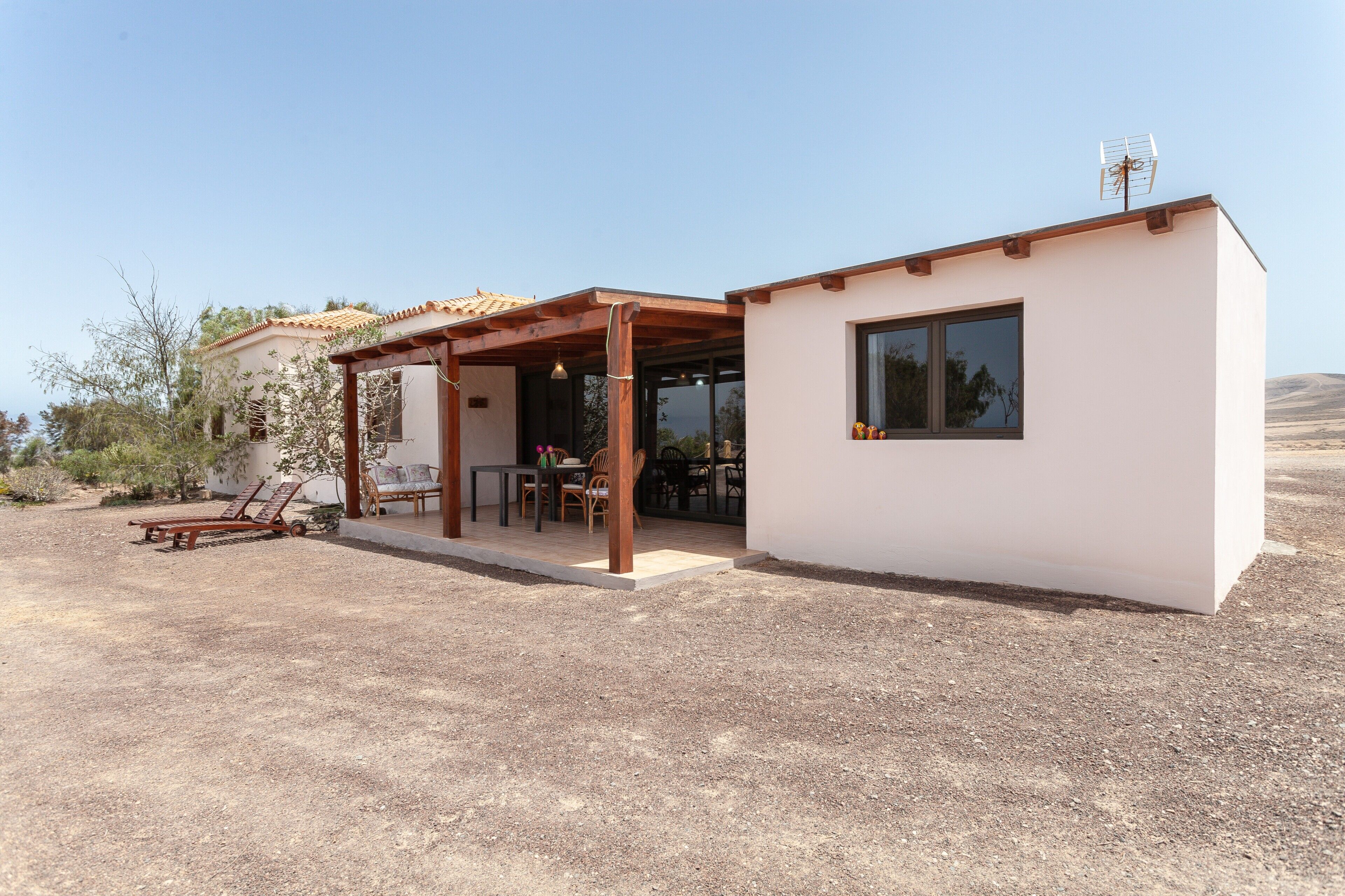 A modern house with a covered patio, a dining area, and a small attached structure.