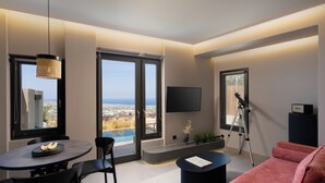Un soggiorno moderno con zona pranzo, ampie finestre, una televisione a schermo piatto, un telescopio e un divano rosa.