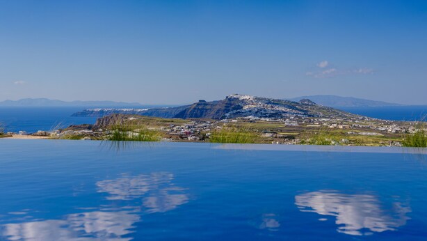 Una piscina con vista su una cittadina costiera e montagne.