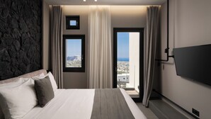 Una camera d'albergo moderna con un letto grande, una televisione a schermo piatto e vista sulla città e sul mare dalla finestra.