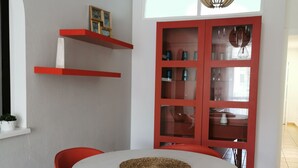 Ein Essbereich mit einem runden Tisch, roten Stühlen, einer roten Schrank mit Glastüren und einer Pendelleuchte.