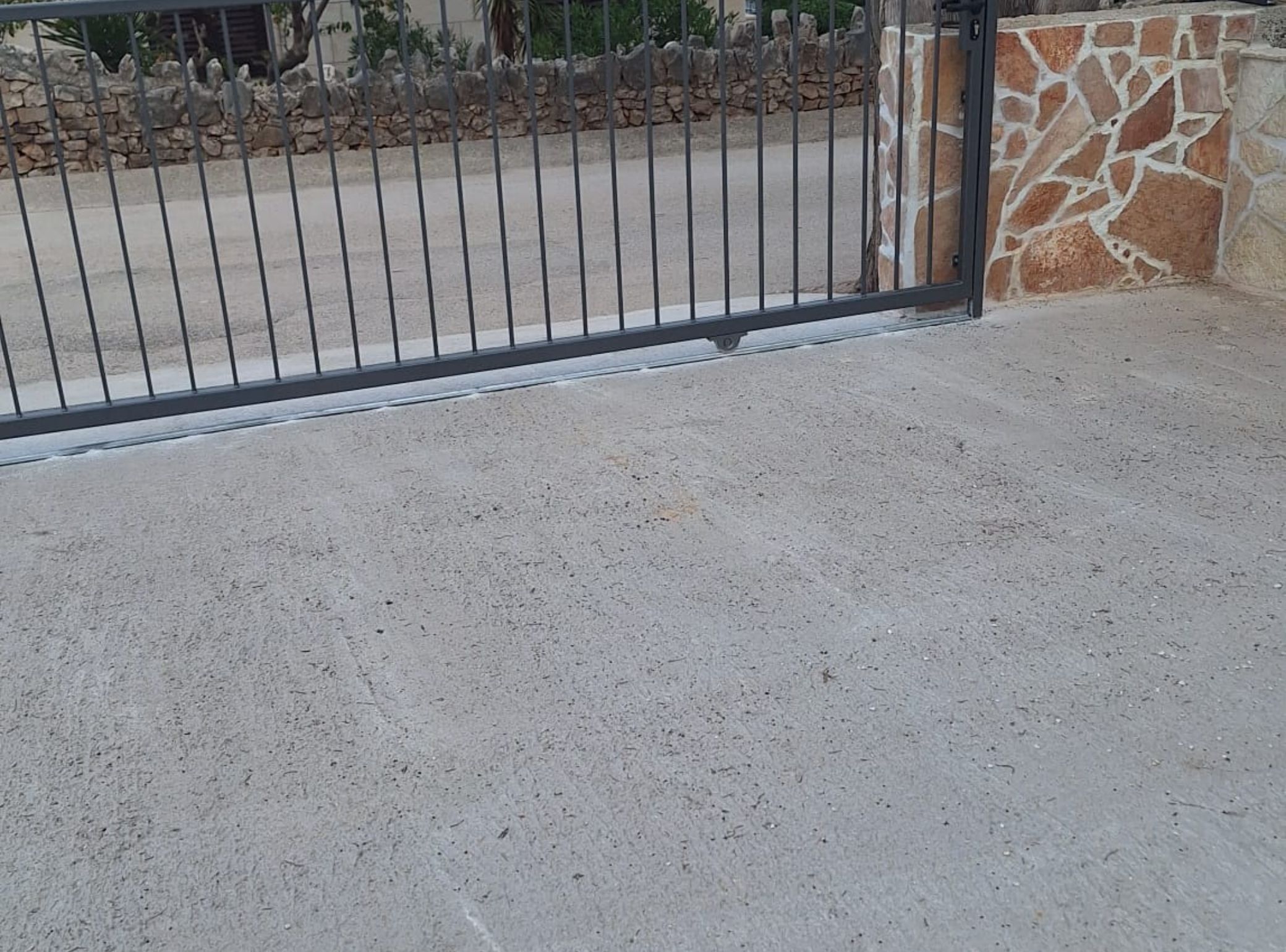Un cancello con pavimento in cemento e muro in pietra.