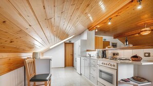 Una cocina con vigas de madera en el techo, una estufa y un lavamanos.