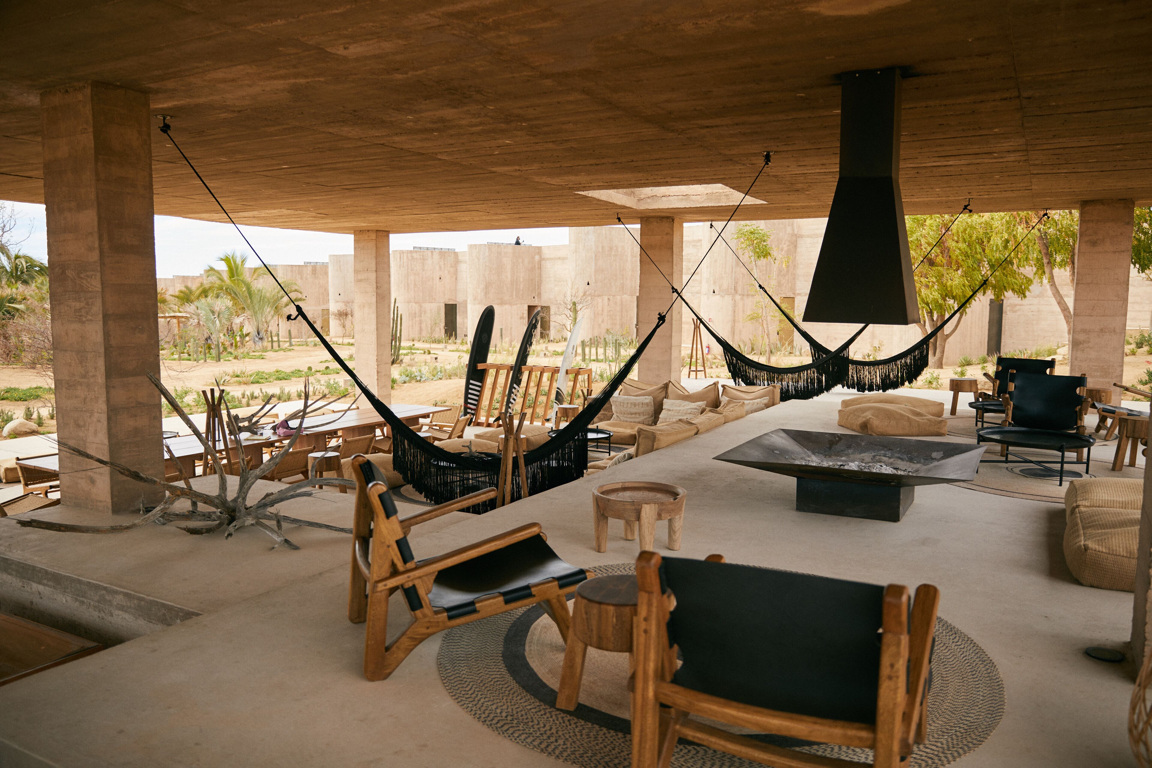 An outdoor seating area with hammocks, wooden chairs, and a fire pit.