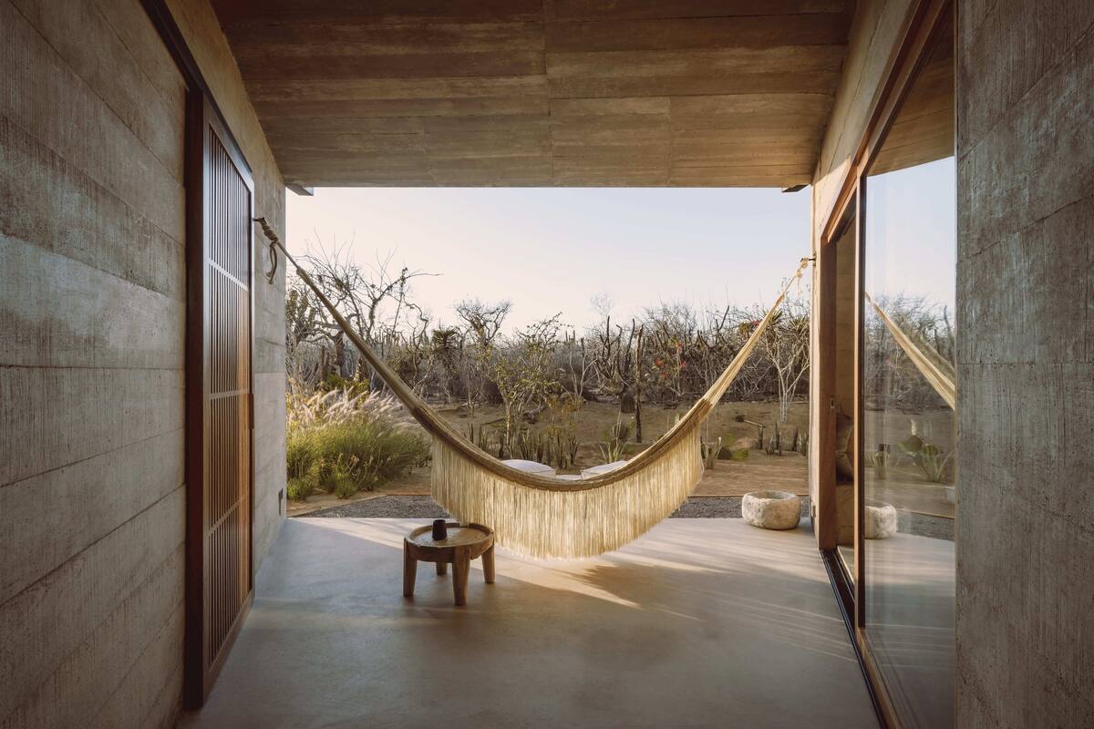 Una hamaca en un espacio moderno y abierto, con vista a un jardín ajardinado.