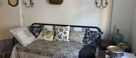 Una habitación acogedora con una cama, una mesita con lámpara y adornos en la pared.