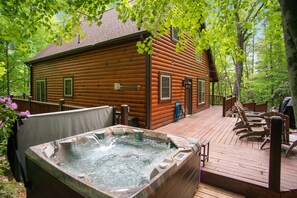 A wooden cabin with a hot tub on a deck, surrounded by trees. - Iron Mountain Lodge 3 Bedroom Cabin by RedAwning (Butler)
