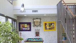 Uma área de estar moderna com mesa de bilhar, assentos confortáveis e obras de arte nas paredes.