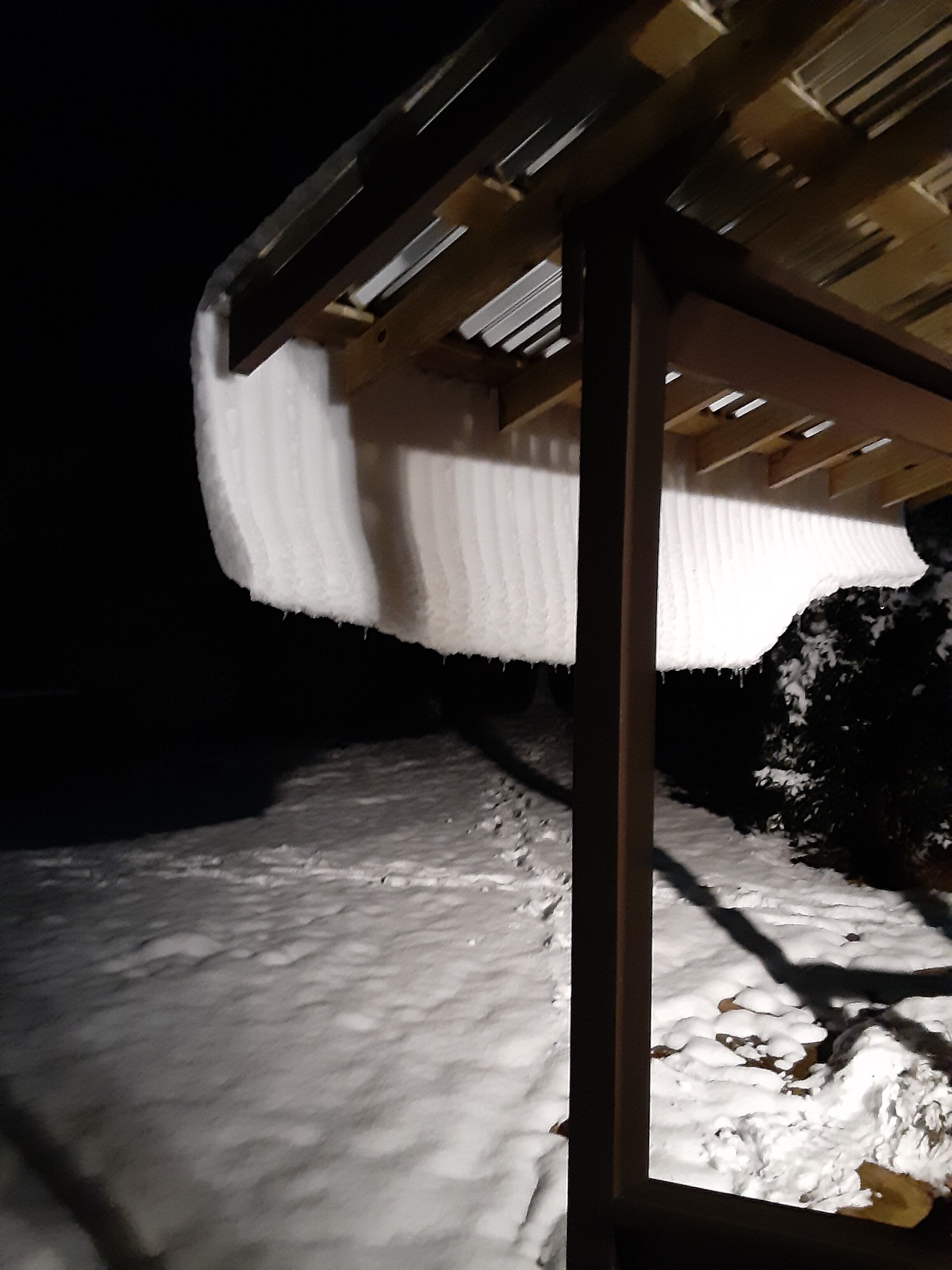 Tejado cubierto de nieve con borbotones de hielo colgando.