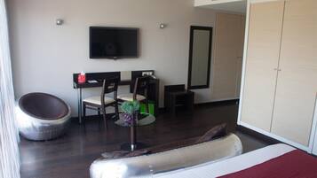 Relax in a spacious room with a large bed, comfortable seating area, and wall-mounted TV.