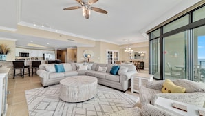 A spacious living area with a large sectional sofa, a round ottoman, and a dining area with a chandelier. - Parking level!  Lazy river/Slide. New to the rental market!! (Orange Beach)