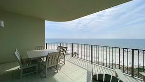 A balcony with a table and chairs, overlooking a beach with a clear view of the ocean. - Parking level!  Lazy river/Slide. New to the rental market!! (Orange Beach)