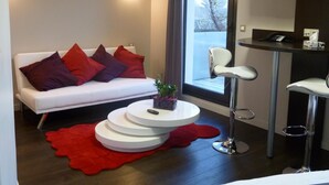 Een moderne woonkamer met een witte bank, rode kussens, een ronde salontafel en een rood vloerkleed.