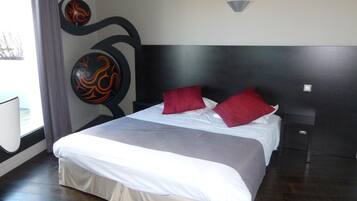 Relax in a spacious room with a large bed, dark wood floor, and a decorative wall art piece.