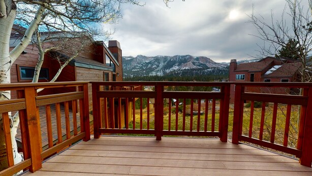 A wooden deck with a view of snow-capped mountains and a clear sky.