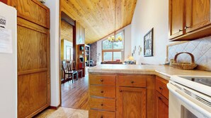 A kitchen with wooden cabinets, a large window, and a dining area with chairs and a table.