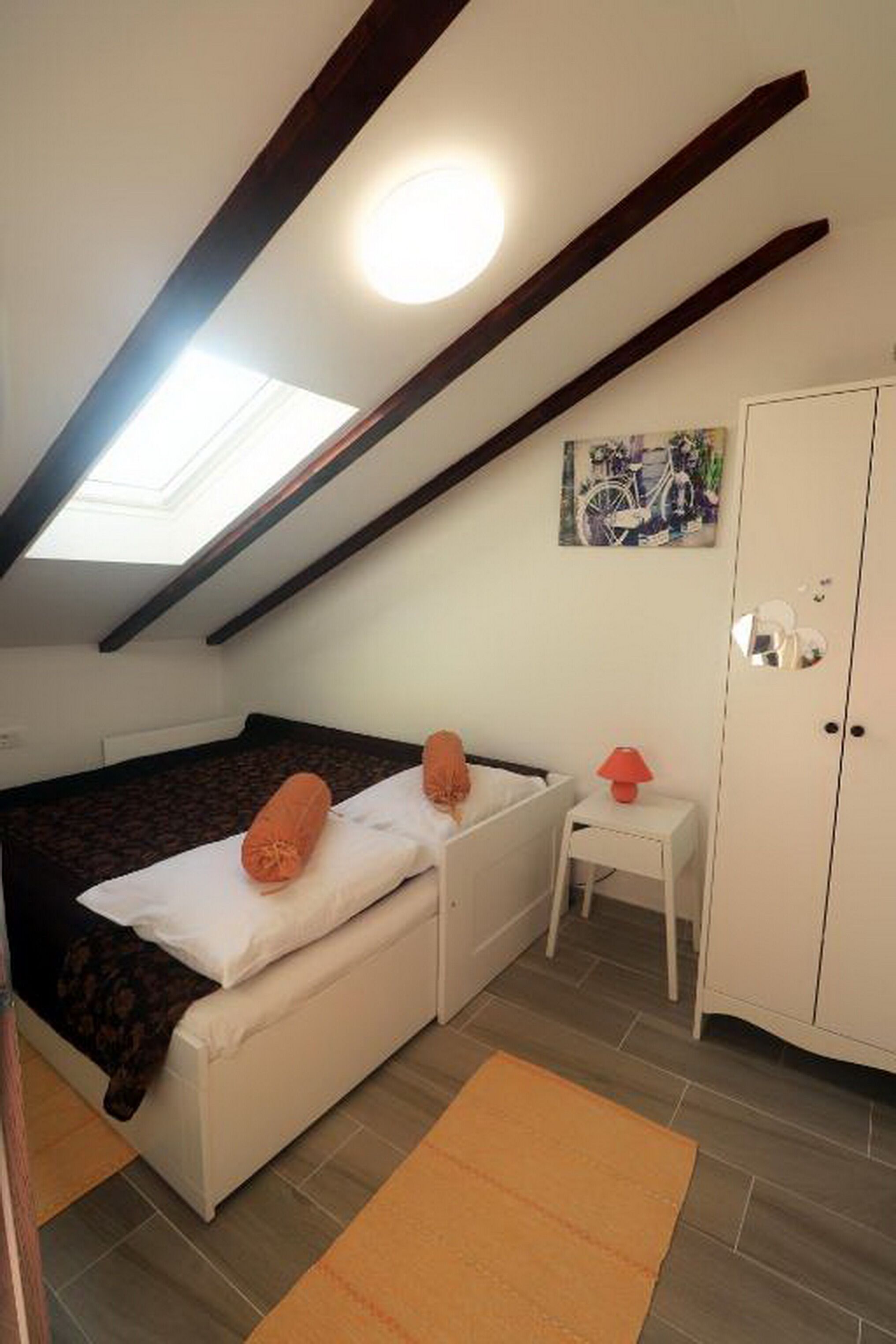 A small, cozy room with a loft bed, a desk, and a wardrobe.