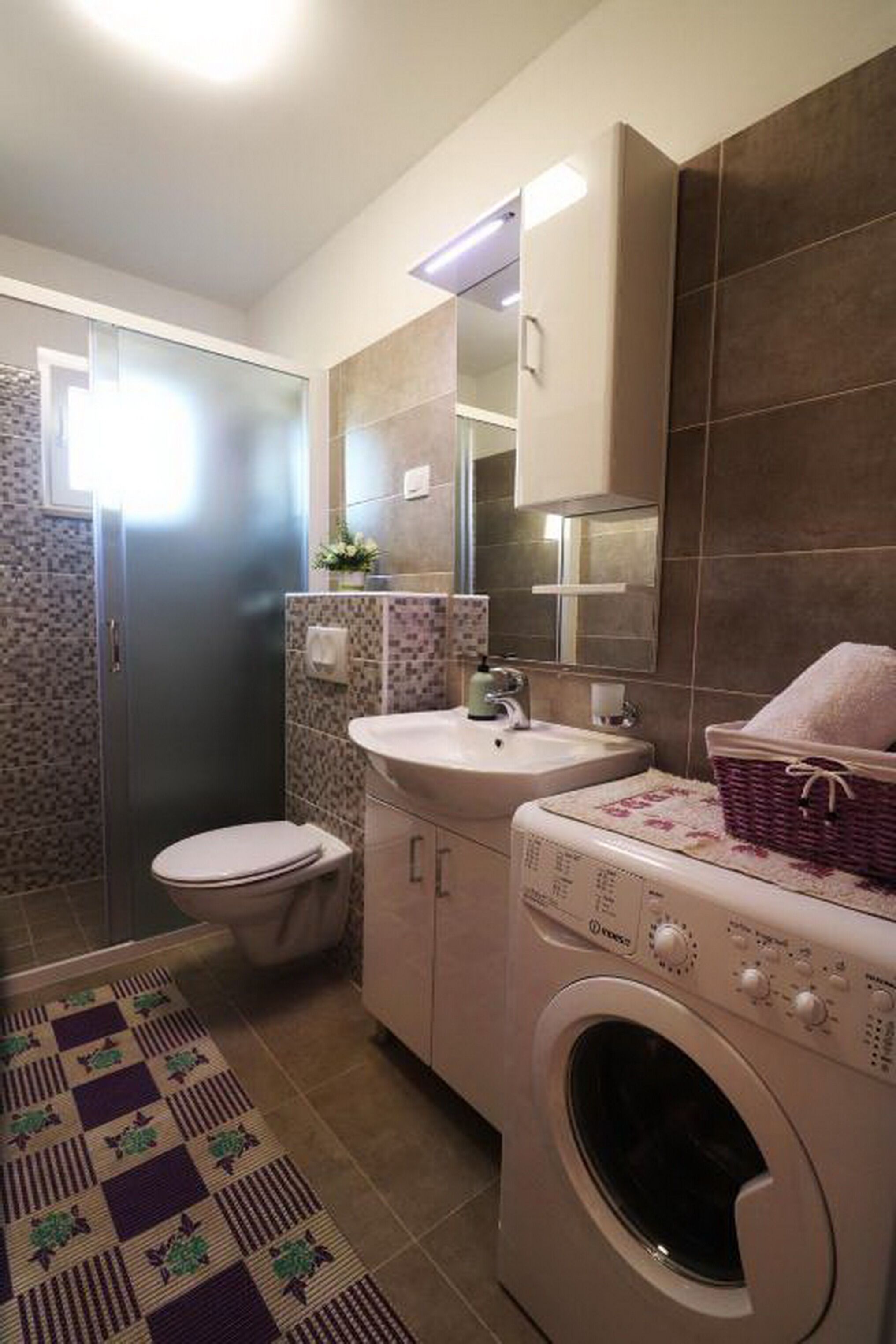 Une petite salle de bain comprenant des toilettes, un lavabo et un lave-linge.