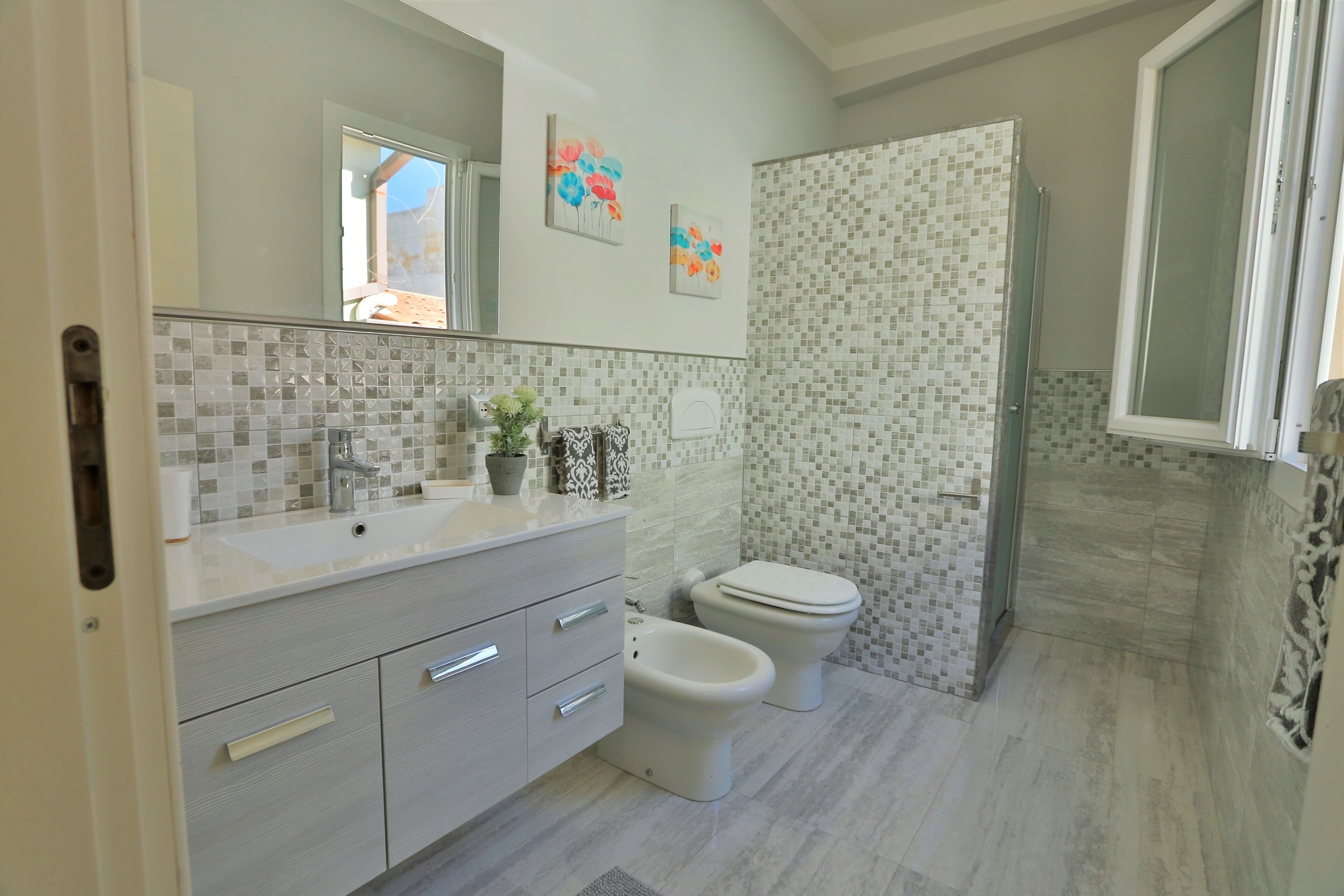 A modern bathroom with a tiled shower, a sink with a mirror, and a toilet.