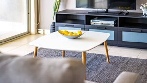 A modern living room with a white coffee table, a bowl of lemons, a television, and a dark entertainment unit. - Hindmarsh Island - Waterfront Luxury, Wi-Fi, Linen (Hindmarsh Island)