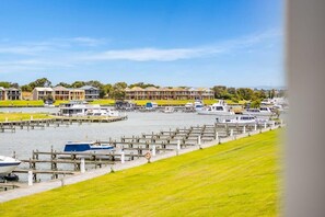 A marina with boats docked, a grassy area, and a row of buildings in the background. - Hindmarsh Island - Waterfront Luxury, Wi-Fi, Linen (Hindmarsh Island)