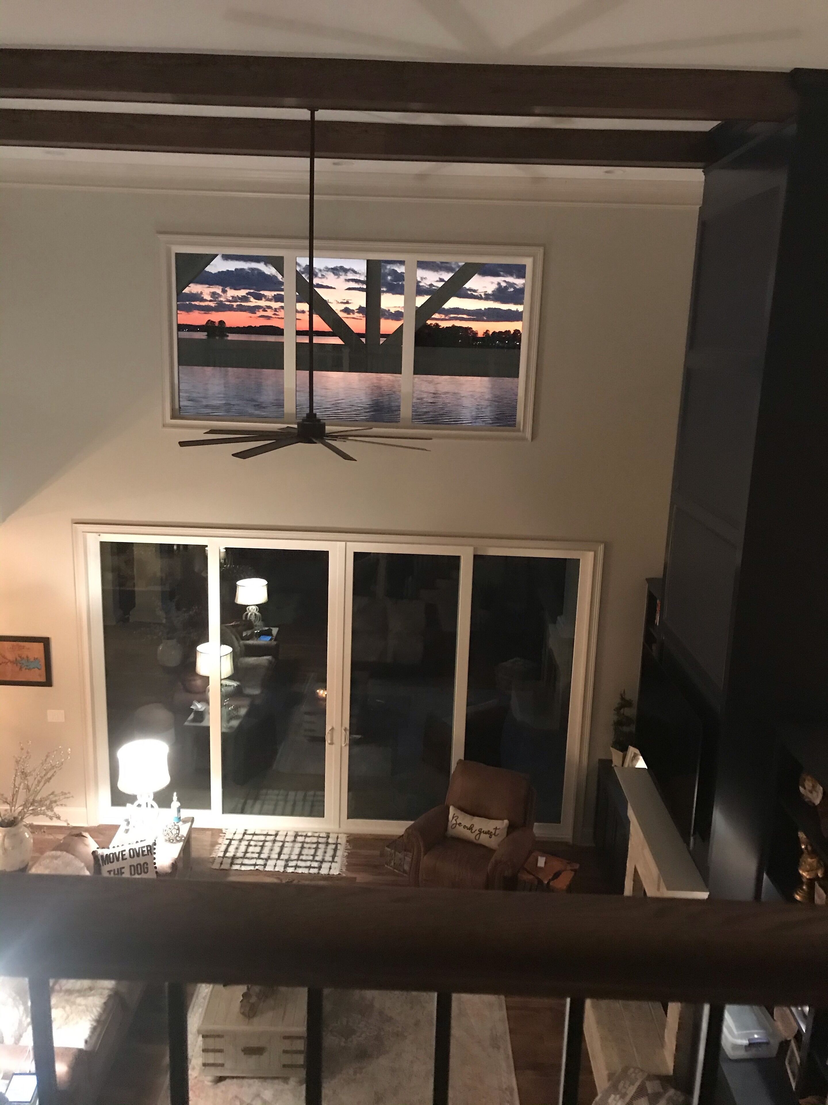 A room with a large window overlooking a scenic view, a ceiling fan, and a sliding glass door leading to an outdoor area.