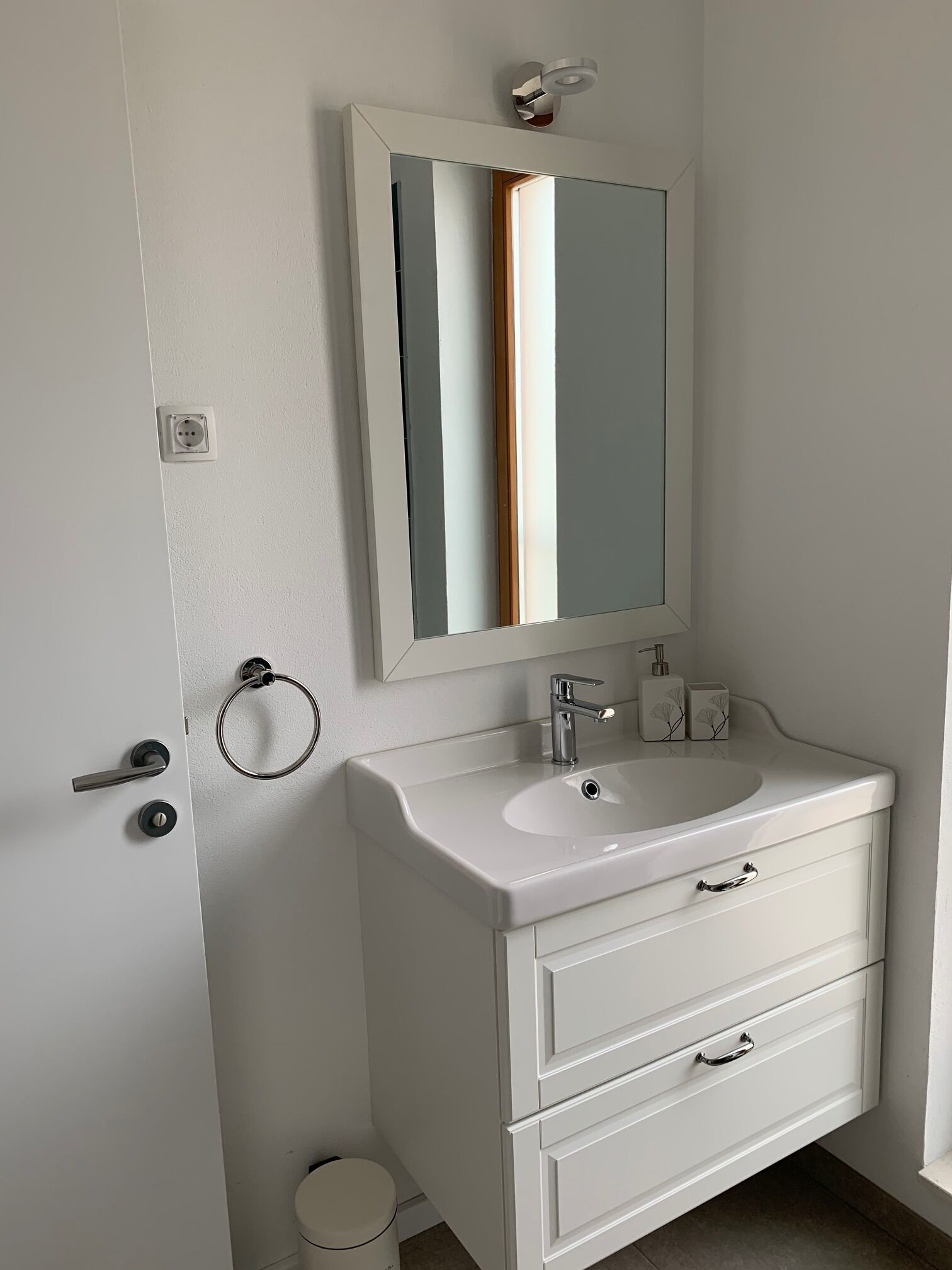 A bathroom with a white sink, a mirror, and a toilet.