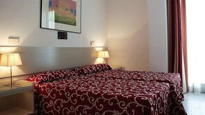A hotel room with two beds, a framed picture on the wall, and two bedside lamps.