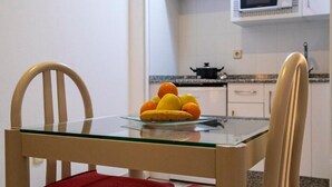 A dining table with chairs, a glass top, and a fruit bowl with oranges and bananas.
