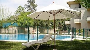 Zona de piscina con una silla de descanso y una sombrilla.
