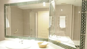 A bathroom with a large mirror, a sink, a shower, and a towel rack.