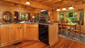 L’intérieur d’un chalet en bois comprend une cuisine, un coin repas et de grandes fenêtres.
